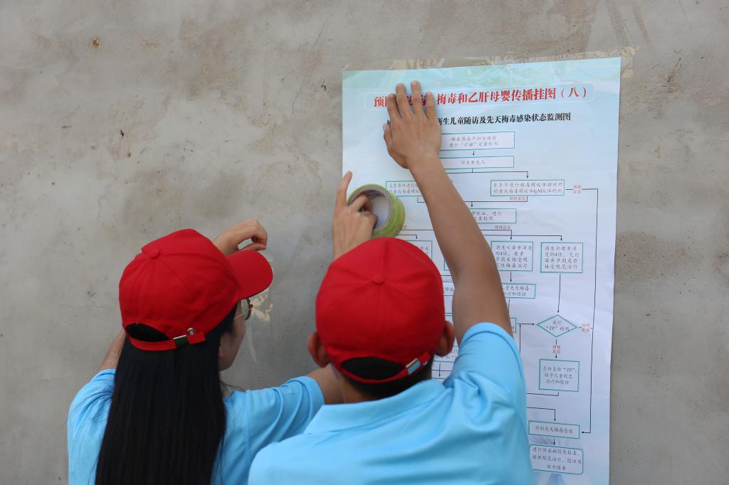 志愿者在孙庄村社区张贴禁毒防艾宣传海报