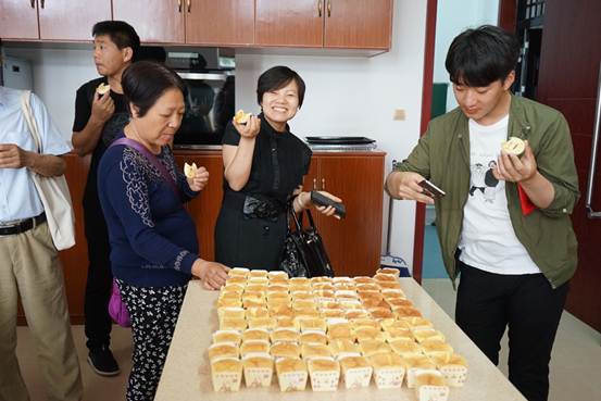 说明:志愿者在烘焙教室品尝课程成品